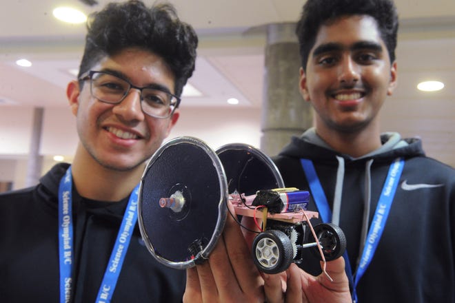 Yash Taneja, left, and Jasheep Dhillon, both 16, with their car that competed in the electric vehicle competition at the Science Olympiad on Saturday at McNair High School. [CALIXTRO ROMIAS/THE RECORD]