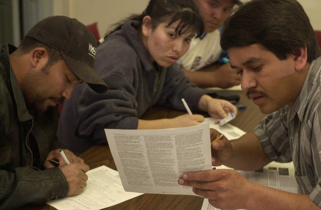 Spanish-language interpreter Victor Hernandez, right, helps people with their tax returns at St. Mary's Catholic Church in this photo published March 5, 2001. The church held tax clinics to help Spanish speakers fill out their tax forms. [STARNEWS FILE]