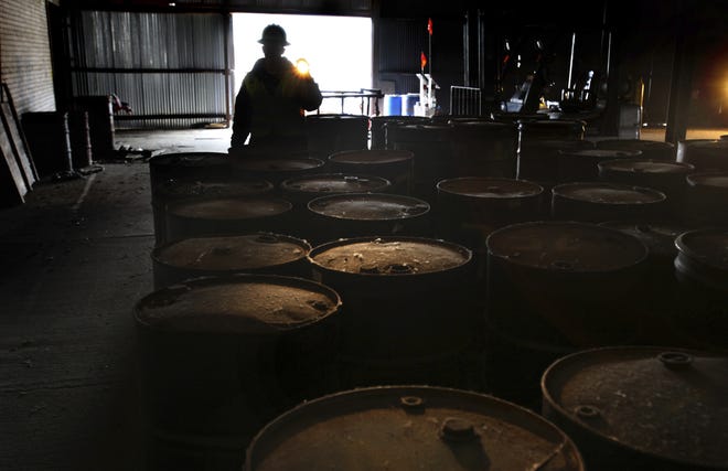 Brian Kelly with the EPA uses a flash light to show barrels of chemicals that have been collected for classification and removal from around the former Rock Tenn paper mill site on Helen Avenue in Otsego, Mich. AP