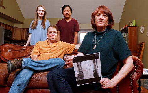 In this Sunday, March 5, 2017, photo, Leslie Kurtz, right, poses for a picture with her husband, Bart Bartram, daughter Rainey, and son Rio as she holds a print of an X-ray of her ankle, in Knoxville, Tenn. Leslie Kurtz needed three plates, eight screws and a big assist from her insurer after breaking every bone in her ankle during a whitewater rafting accident in 2015. Coverage she purchased through a public insurance exchange established by the federal health care law helped with her medical expenses, but that protection may not exist next year because insurers have abandoned her exchange. (AP Photo/Wade Payne)