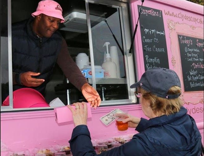 Dale Ciardelli of East Kingston purchases cupcakes from Clyde Bullen of Clyde’s Cupcakes at the New Hampshire Food Truck Festival last October at Redhook Brewery. The city of Portsmouth is initiating a pilot program to allow food trucks to operate in the late evening and early morning around the High-Hanover parking garage. [Suzanne Laurent photo, file]