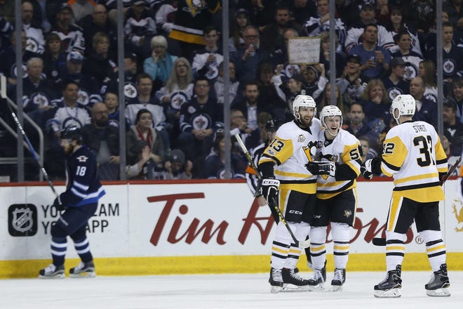 Winnipeg Jets' Bryan Little (18) skates past as Pittsburgh Penguins' Nick Bonino (13), Jake Guentzel (59) and Mark Streit (32) celebrate Bonino's third goal of the night, during the second period of the Penguins' 7-4 win Wednesday in Winnipeg, Manitoba.