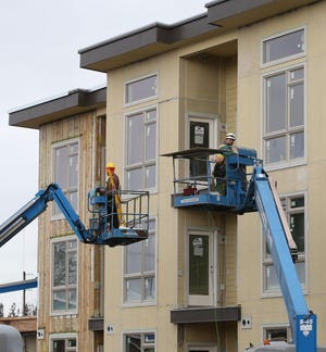 Construction works add trims to the outside of an apartment complex being built in north Eugene by John Hyland Construction. (Chris Pietsch/The Register-Guard)