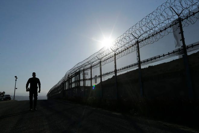 In this June 22, 2016 photo, a Border Patrol agent walks along a border structure in San Diego, Calif. The U.S. Border Patrol's parent agency may exempt many veterans and law enforcement officers from a requirement that new hires take a lie-detector test. (AP Photo/Gregory Bull, file)