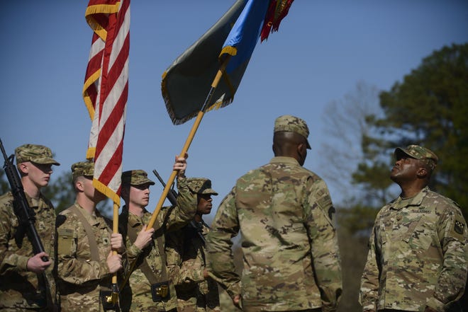 Col. James E. Walker, far right, looks up as the colors of the 525th Military Intelligence Brigade before he and Command Sgt. Maj. Edward Baptiste case the brigade's colors at Fort Bragg on Thursday. [Staff photo by Melissa Sue Gerrits]