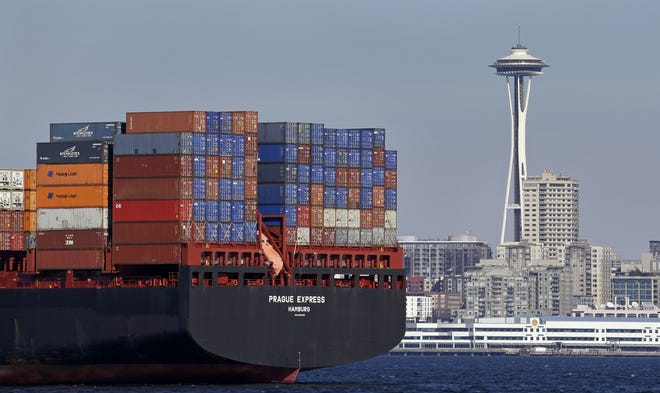 In this Feb. 15, 2015, file photo, the Space Needle towers in the background beyond a container ship anchored in Elliott Bay near downtown Seattle. U.S. employment numbers were released Friday. [AP Photo/Elaine Thompson, File]