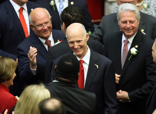 Gov. Rick Scott, center, greets legislators as he makes his way to the podium Tuesday to make the State of the State address. [AP Photo/Steve Cannon]