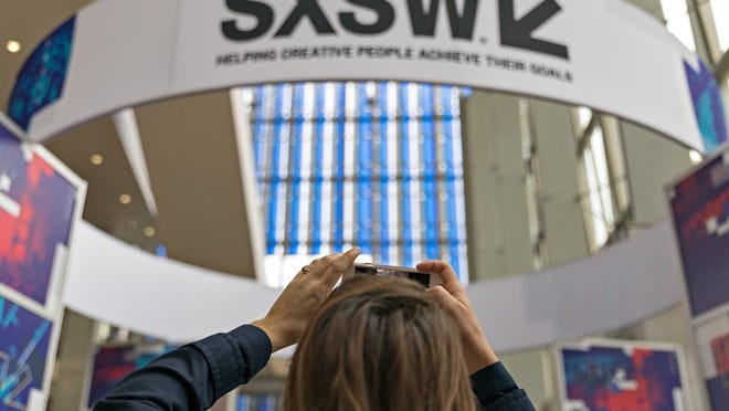 SXSW attendee Natalie Fernandez takes photos of a SXSW banner in the Austin Convention Center on Saturday March 11, 2017. Daulton Venglar/AMERICAN-STATESMAN