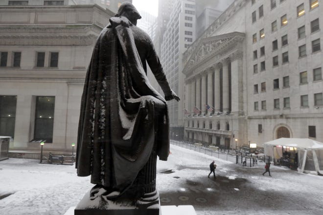 The statue of George Washington on the steps of Federal Hall overlooks the New York Stock Exchange, right, during a winter storm, Tuesday, March 14, 2017. Global stocks drifted lower on Tuesday as investors looked to the Federal Reserve's policy meeting for an expected interest rate increase and hints on future hikes. THE ASSOCIATED PRESS