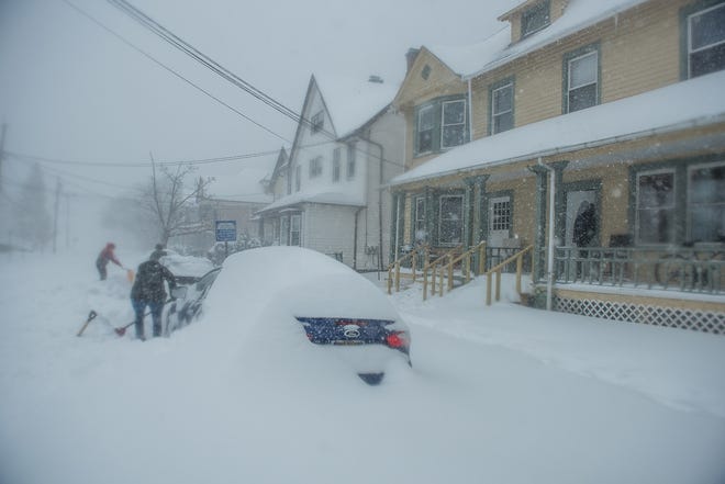 Kingston residents on Delaware Avenue dig out their cars to avoid getting tickets during Tuesday's storm. [KELLY MARSH/FOR THE TIMES HERALD-RECORD]