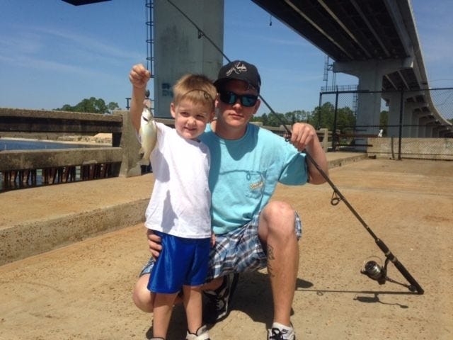 Three-year-old Colten Griffin, here with his father Wes, shows off his first fish, caught from the West Bay Bridge.
