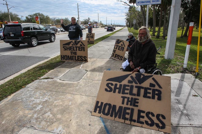 Pastor Mike Pastore (left) stands next to a volunteer and homeless men during the "Shelter the homeless" protest at the corner of Nova and International Speedway Boulevard in Daytona Beach on Jan. 28. News-Journal / LOLA GOMEZ