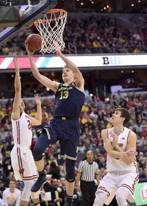 Michigan forward Moritz Wagner (13) goes to the basket against Wisconsin's Bronson Koenig, left, and Ethan Happ, right, during the second half of an NCAA college basketball game for the Big Twn tournament title, Sunday, March 12, 2017, in Washington. Michigan won 71-56. (AP Photo/Nick Wass)