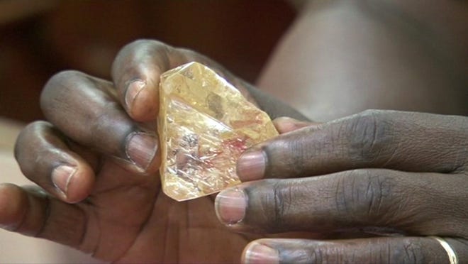 In this photo taken from video footage, Sierra Leone's President Ernest Bai Koroma hands a diamond during a meeting with delegates of Kono district, where the gem was found, at the presidential office in Freetown, Sierra Leone, Thursday, March 16, 2017. THE ASSOCIATED PRESS