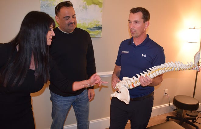 Dr. Adam Zimmerman, right, explains different chiropractic services that he offers at his office to Christine Dey and Jose Martinez during ribbon cutting ceremony for his new chiropractic sports office on Thursday. [ABRAHAM GALVAN/ THE LOG]