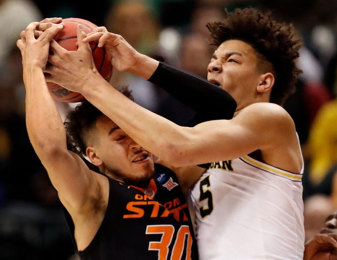 Oklahoma State's Jeffrey Carroll, left, and Michigan's D.J. Wilson reach for a rebound during the first half of a first-round game in the men's NCAA college basketball tournament Friday, March 17, 2017, in Indianapolis, Mo. (AP Photo/Jeff Roberson)