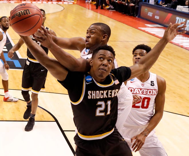 Wichita State's Darral Willis Jr. (21) and Dayton's Kendall Pollard reach for a rebound as Dayton's Xeyrius Williams (20) watches during the first half of a first-round game in the men's NCAA college basketball tournament Friday, March 17, 2017, in Indianapolis. (AP Photo/Jeff Roberson)