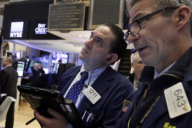 Traders Tommy Kalikas, left, and Ronald Madarasz work on the floor of the New York Stock Exchange. THE ASSOCIATED PRESS