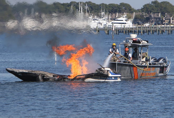 Firefighters work to extinguish a boat fire in Grand Lagoon on Friday near Panama City Beach. Three people were fueling the boat when it somehow caught fire. Out of fear the flames would spread to the fueling station, people nearby pushed the boat into the open water of the lagoon, U.S. Coast Guard officials reported. See video from the fire at newsherald.com. [ANDREW WARDLOW/THE NEWS HERALD]