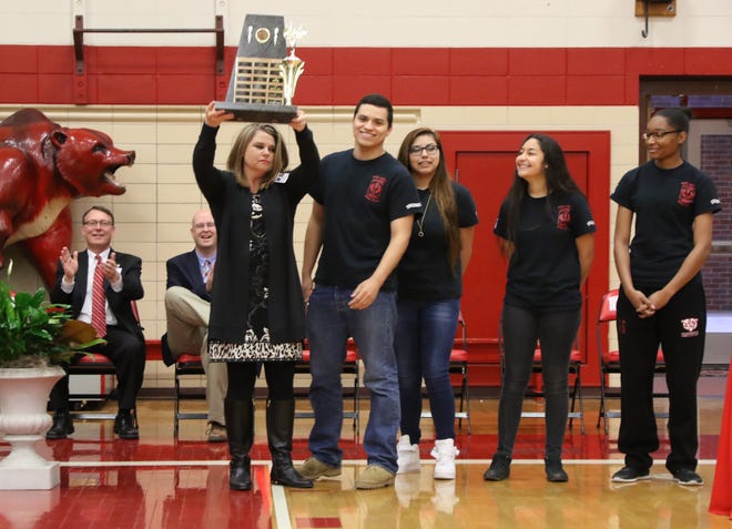 Northside High School Principal Dr. Ginni McDonald hoists the 2017 Arkansas State JROTC Precision Air Rifle trophy Thursday, March 16, 2017, after a presentation by Northside JROTC team members Javier Mendez, from left, Denise Quirarte, Kim Sandoval and Eboni Robinson during a special assembly in Kaundart Grizzly Fieldhouse. The Grizzly Battalion JROTC shooters have won 15 of the 18 Arkansas Precision Air Rifle Championships with first-year shooter Robinson claiming third place in the overall individual titles. [JAMIE MITCHELL/TIMES RECORD]