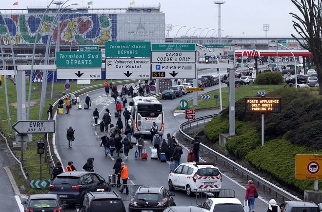 Travellers walk on the highway to the Orly airport, south of Paris, Saturday, March, 18, 2017. A man was shot to death Saturday after trying to seize the weapon of a soldier guarding Paris' Orly Airport, prompting a partial evacuation of the terminal, police said. (AP Photo/Thibault Camus)
