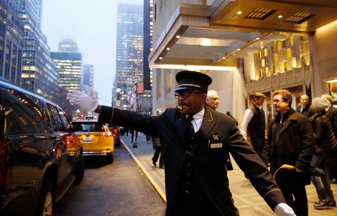 Doorman Thales Cade hails a cab last month in front of the Waldorf Astoria hotel in Manhattan.  Stonewood Luxury Apartments, a planned 20-unit transformation of the old Julian Hotel, will bring back doormen to Peoria. (AP Photo/Kathy Willens)
