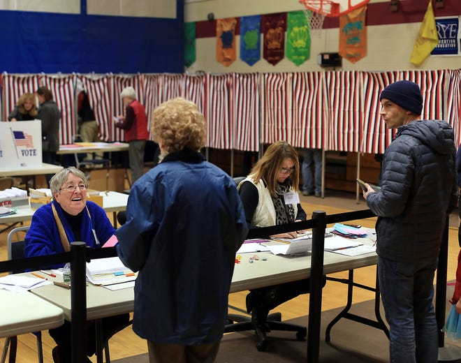 Election inspector Connie Olson, left, checks in voters at Rye Elementary School during town voting on Saturday. [Ioanna Raptis/Seacoastonline]