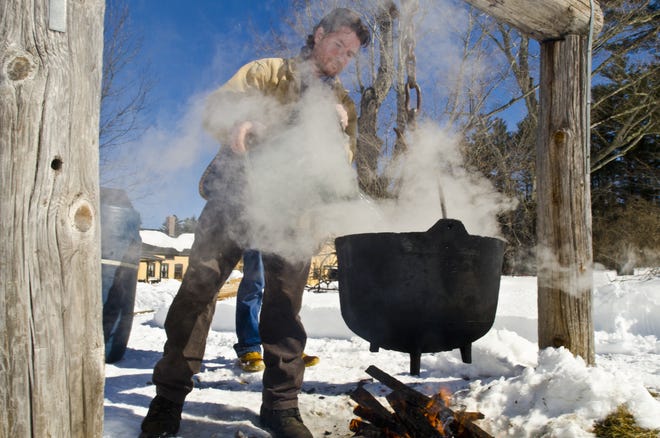 Mark Foynes, director of the New Hampshire Farm Museum, pours sap into a caldron over an outside fire pit during a sap boiling demonstration where visitors learned about the lengthy process that involved in rendering large quantities of liquid into a few sweet ounces of maple syrup at the Farm Museum in Milton Saturday. [Daryl Carlson/Fosters.com]