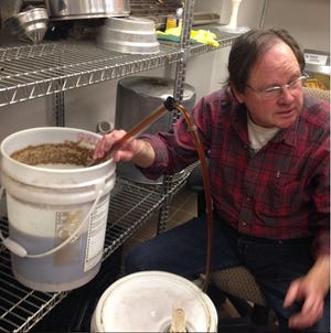 J. Reid speaks to students at the Introduction to Craft Beer Brewing class at Cleveland Community College as he siphons a beer brewed in class to a secondary fermenter. [Courtesy of J. Reid]