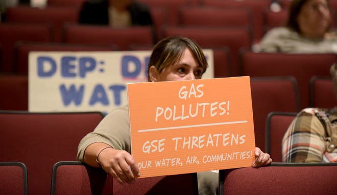 A woman in the audience at Bordentown Regional High School holds a sign protesting the proposed pipeline during Thursday's public hearing on a utility company's application for a wetlands permit needed by the company to build a natural gas compressor station on land off Route 528.