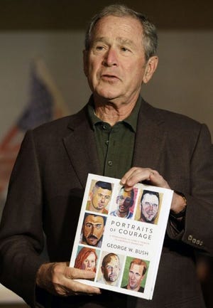 Former President George W. Bush holds a copy of his new book during a press preview of an exhibition of his paintings of U.S. military veterans in Dallas, Tuesday, Feb. 28, 2017. The book titled, "Portraits of Courage: A Commander in Chief's Tribute to America's Warriors," features paintings of U.S. military veterans by their former commander In chief.