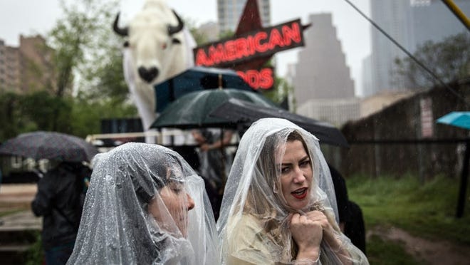Ella Mielniczenko and Kelsey Darragh make their way from Rainey St. to the Austin Convention Center on a rain-soaked second day of SXSW on March 11, 2017. (Tamir Kalifa/ AMERICAN-STATESMAN)