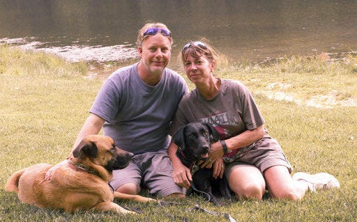 In this Aug. 22, 2015 photo provided by Amy Hunter, John and Amy Hunter are pictured with their dogs, Apollo, left, and Rubi, a black Labrador retriever, in Brown County State Park south of their home in Indianapolis, Ind. The couple is childless by choice and Amy is a stay-at-home pet mom. (Amy Hunter via AP)