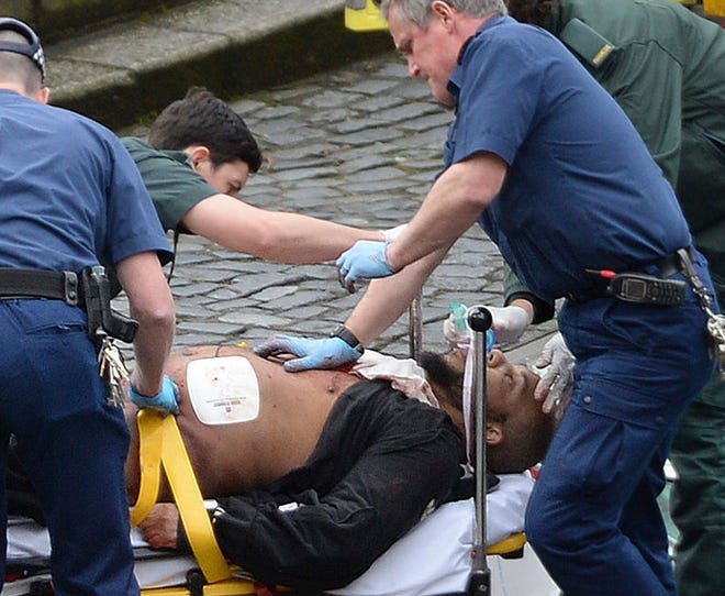 An attacker is treated by emergency services outside the Houses of Parliament London, Wednesday, March 22, 2017. London police say they are treating a gun and knife incident at Britain's Parliament "as a terrorist incident until we know otherwise." The Metropolitan Police says in a statement that the incident is ongoing. It is urging people to stay away from the area. Officials say a man with a knife attacked a police officer at Parliament and was shot by officers. Nearby, witnesses say a vehicle struck several people on the Westminster Bridge. (Stefan Rousseau/PA via AP).