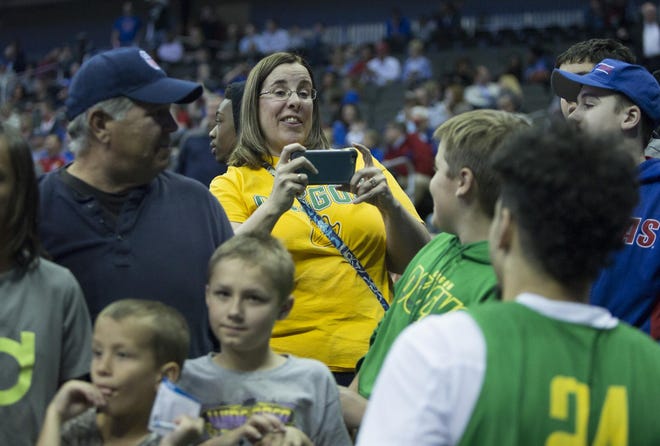 Duck fan Tori Murray takes a photograph of her son, Miller Murray, with Oregon's Dillon Brooks to sign an autograph after the Ducks' open practice in preparation for their NCAA Regional Semifinal at the Sprint Center in Kansas City, Mo. Tori Murray, a graduate of the University of Oregon now living in Kansas City, was one a few Oregon fans in attendance for the practice. (Andy Nelson/The Register-Guard)