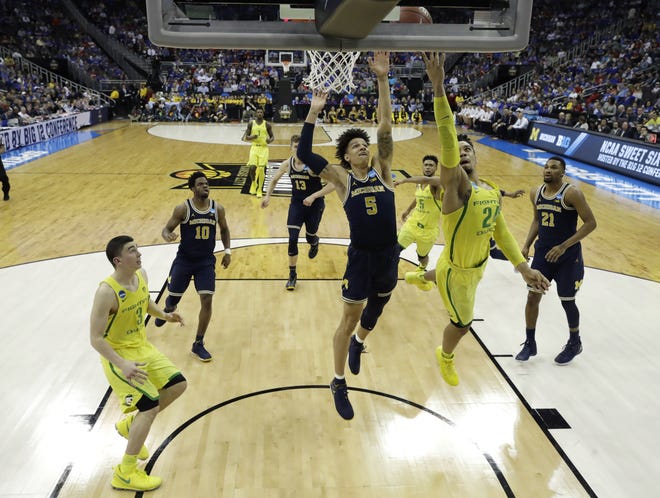 Oregon forward Dillon Brooks drives to the basket ahead of Michigan forward D.J. Wilson (5) during the second half of a regional semifinal of the NCAA men's college basketball tournament on Thursday in Kansas City, Mo. [AP Photo/Charlie Riedel]