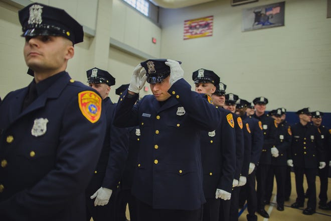 Matias Ferreira, center, adjusts his hat during his graduation ceremony from the Suffolk County Police Department Academy on Friday. Ferreira, a former Marine Corps lance corporal, lost his legs below the knee when he stepped on a hidden explosive in Afghanistan in 2011. [THE ASSOCIATED PRESS]