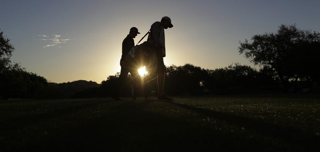 Jon Rahm, left, of Spain, and his caddie walk off of the tee box on the first hole during the round of 16 play at the Dell Technologies Match Play golf tournament at Austin County Club, Saturday in Austin, Texas. [ERIC GAY / ASSOCIATED PRESS]