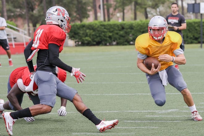 Nicholls State University quarterback Chase Fourcade (right) runs with the football in front of safety Corey Abraham (31) during Saturday's scrimmage at John L. Guidry Stadium.