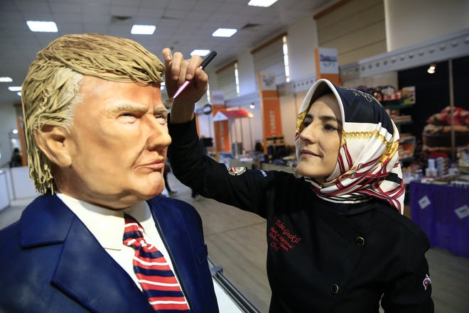 Turkish pastry chef Tuba Geckil adds the finishing touches to her figure of U.S. President Donald Trump made out of cake icing during a chocolate show in Istanbul on Saturday. [Lefteris Pitarakis/AP]