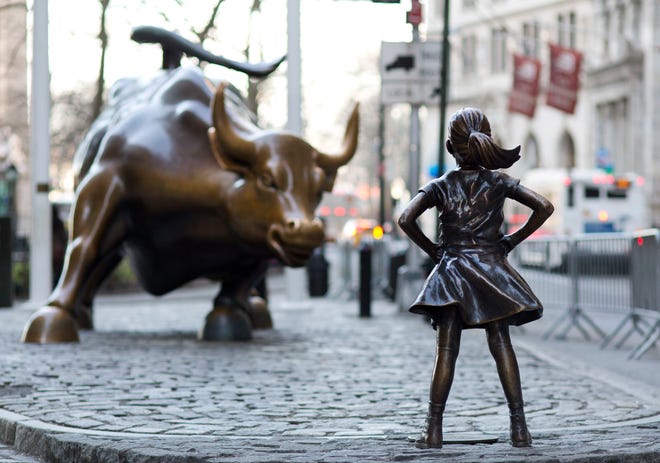 In this March 22, 2017 photo, the Charging Bull and Fearless Girl statues are sit on Lower Broadway in New York. Since 1989 the bronze bull has stood in New York City's financial district as an image of the might and hard-charging spirit of Wall Street. But the installation of the bold girl defiantly standing in the bull's path has transformed the meaning of one of New York's best-known public artworks. Pressure is mounting on the city to let the Fearless Girl stay. (AP Photo/Mark Lennihan)