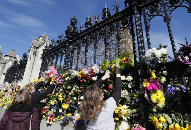 People place flowers outside Britain's parliament in London, Saturday March 25, 2017, for the victims of the Westminster attack on Wednesday. Khalid Masood killed four people and left more than two dozen hospitalized, including some with what have been described as catastrophic injuries. THE ASSOCIATED PRESS
