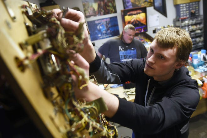 Nathan Goett, 20, restores a Jurassic Park pinball machine while his dad Dan Goett, 46, cleans parts of another machine at the Pinball Company on Tuesday, March 14, 2017. Dan and Nathan have been pinball technicians with the company since 2013.