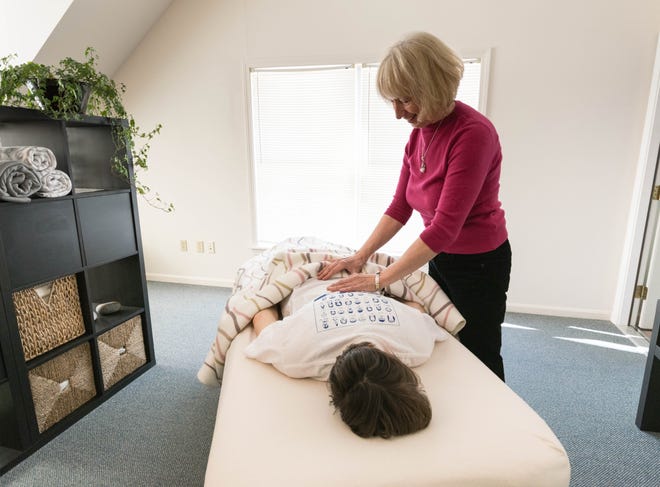 Bowenwork practitioner Ainslee Farrington performs a series of light touches on colleague Juliet Altham in their Kennebunk office. The touches stimulate nerve endings, which initiate the self-healing process. 

[Kathy Eow photo]