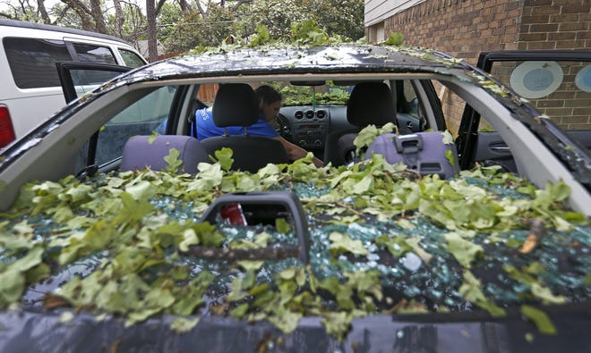 Tara Shadoan takes her belongings before the insurance company tows her car damaged by a hailstorm in Highland Village, Texas, on Monday. The springtime severe weather season is ramping up with damaging winds, large hail and tornadoes in the forecast nearly every day this week. (Jae S. Lee/The Dallas Morning News via AP)