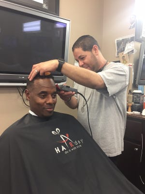 Jose Rivera, manager at Shaggy's Barber Shop, gives Bernard Goshay a trim at the Palm Coast shop. [News-Tribune photos/Aaron London]