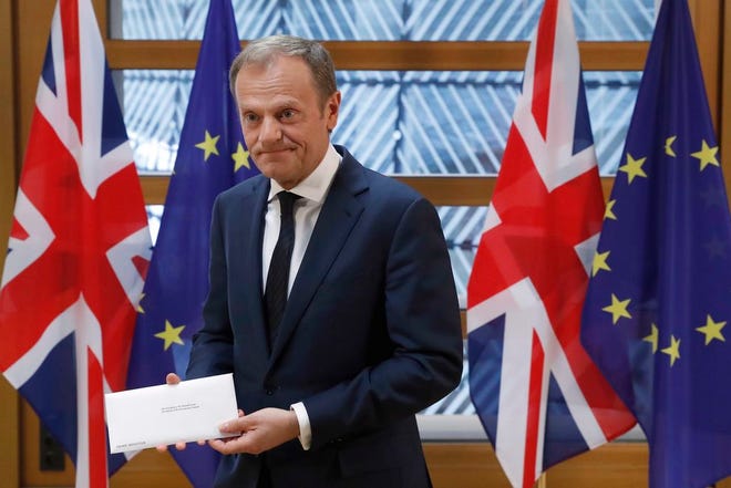 EU Council President Donald Tusk holds British Prime Minister Theresa May's Brexit letter which was delivered by Britain's permanent representative to the European Union Tim Barrow that gives notice of the UK's intention to leave the bloc under Article 50 of the EU's Lisbon Treaty, in Brussels, Belgium, Wednesday, March 29, 2017. Barrow hand-delivered the letter signed by Britain's Prime Minister Theresa May that will formally trigger the beginning of Britain's exit from the European Union. (Yves Herman/Pool Photo via AP)