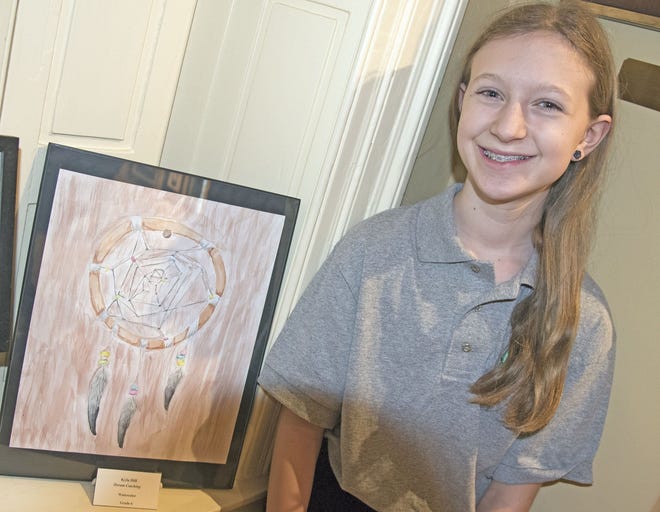 Kyla Hill poses next to her dreamcatcher water color on display at the Woodman Museum. [John Huff/Fosters.com]