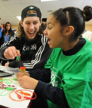 Tansey fourth grader Brisia Rodriguez Castillo gets some help from Celtics center Kelly Olynyk as she works on a scientific experiment.