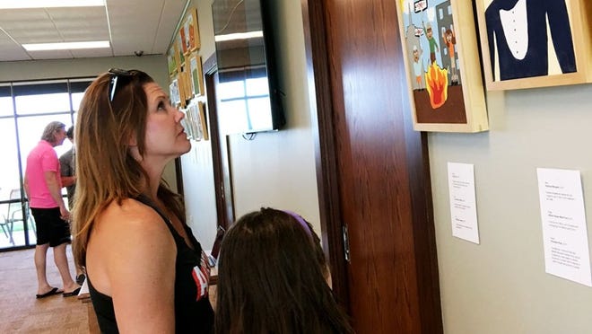 Kathleen Wotring and daughter Savannah admire artwork by Valley View Elementary School students during a reception for the Immigration Series Sunday at the Laura Bush Community Library. TED ALLEN/WESTLAKE PICAYUNE